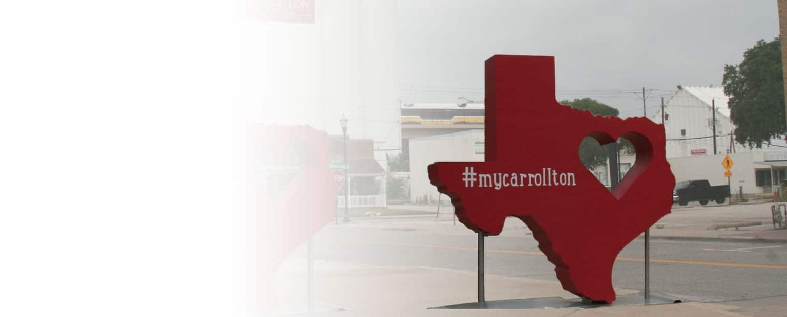 Texas sign in the shape of Texas state with hashtag my Carrollton with a heart in the center.